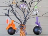 black branches placed in a vase wrapped with orange ribbons, with black and sheer glass ornaments and colorful ribbons