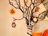 black branches in a striped vase, with colorful paper ornaments is a creative and easy idea of a Halloween tree