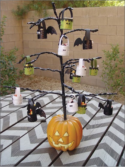 a black Halloween tree decorated white, green and black glitter lanterns and inserted into a pumpkin