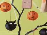 black branches with black cat heads and orange pumpkins of paper hanging and paper bags for a Halloween tree