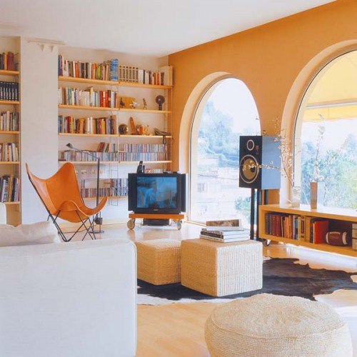 a mid-century modern living room with open bookshelves attached to the wall and a floor book storage unit next tot he window