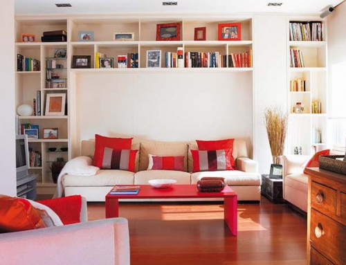 a living room with a large book storage unit over the sofa that can hold a lot of books and other stuff without taking floor space