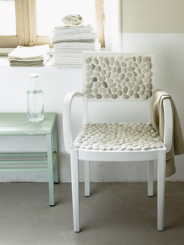 a white chair with a back and seat covered with pebbles is a great furniture piece for a beach home