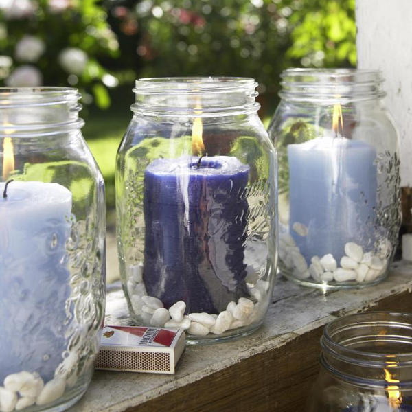 large jars with purple and lilac candles plus some white pebbles inside are great for indoor and outdoor decor