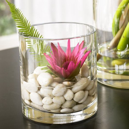 a glass with pebbles and water plus a leaf and a bold bloom is a beautiful arrangement for home decor
