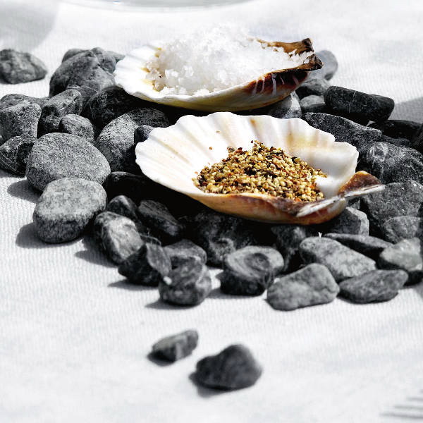 pebbles placed on the table, with shells filled with condiments is a creative idea of a sea tablescape