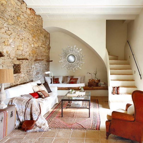 a living room with a bench under the stairs, spruce it up with pillows and blankets
