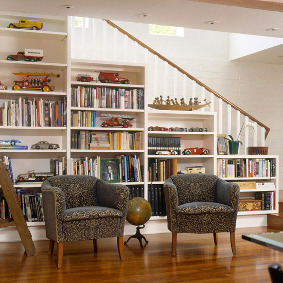 a staircase with whole bookcases under it   place a couple of chairs and you'll get a ready reading space