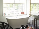 a retro bathroom with vintage black furniture,black shades, an oval tub and a large ornate mirror in front of the tub
