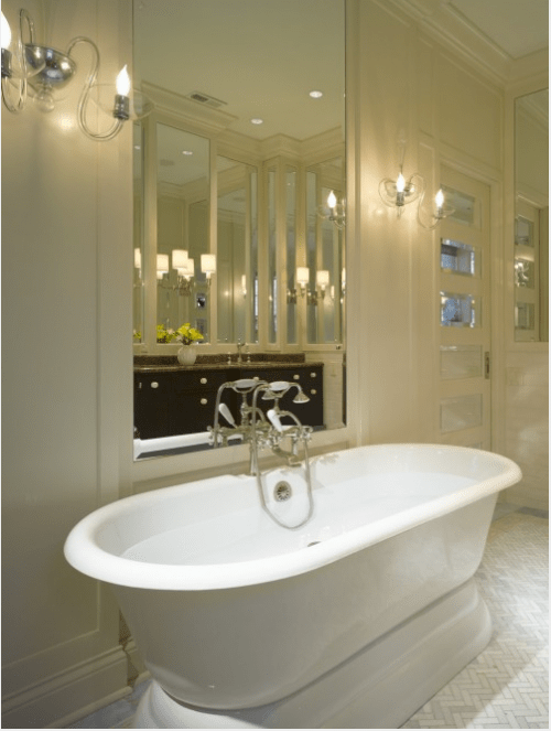 a neutral luxurious bathroom with retro touches, a retro tub, vintage fixtures and a mirror over the tub