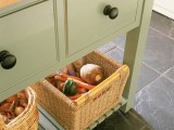 a green kitchen island with an open storage space, a couple of baskets for storing vegetables and fruits with a rustic touch