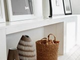 a white narrow console table and a basket for storage firewood is a decoration that adds coziness to the space