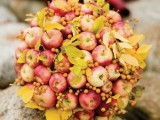 a fall centerpiece of fall apples, fall leaves and berries is a lovely decoration in bright shades