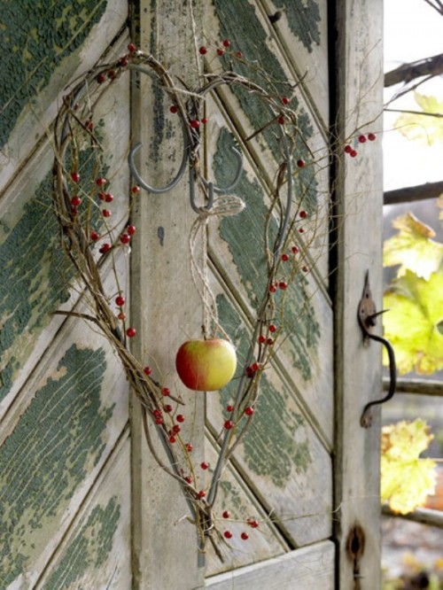 a creative vine heart-shaped wreath with berries and a fall apple in the center is great for outdoors and indoors