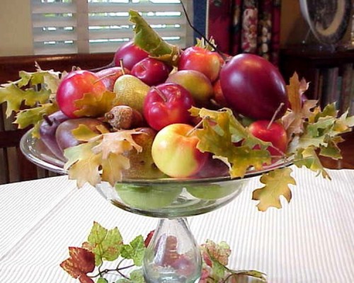 a glass bowl with pears, apples, fall leaves and acorns is a gorgeous fall centerpiece