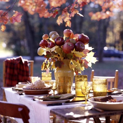 a cool and easy rustic fall centerpiece of a mustard vase with natural fall leaves and red apples is very yummy