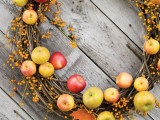 a vine wreath with fall leaves, berries and bright apples is a beautiful and easy rustic decoration for the fall
