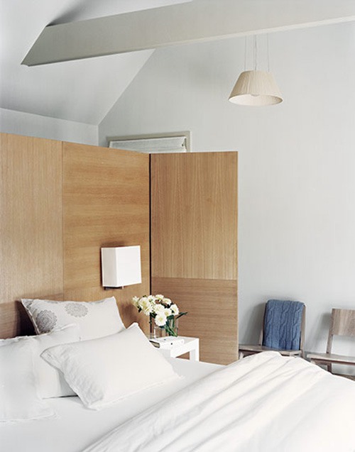 a modern light colored plywood space divider adds warmth to the bedroom and separates it from the bathroom