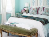 a bright framed botanical space divider as a headboard that matches the turquoise walls in the space