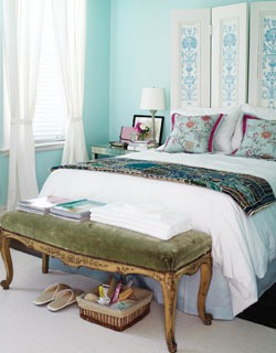 a bright framed botanical space divider as a headboard that matches the turquoise walls in the space