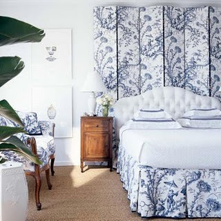 the bed covered with blue and white fabric and a space divider upholstered with the same to match and create a cohesive space