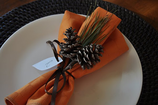 table setting with orange napkins and pinecones