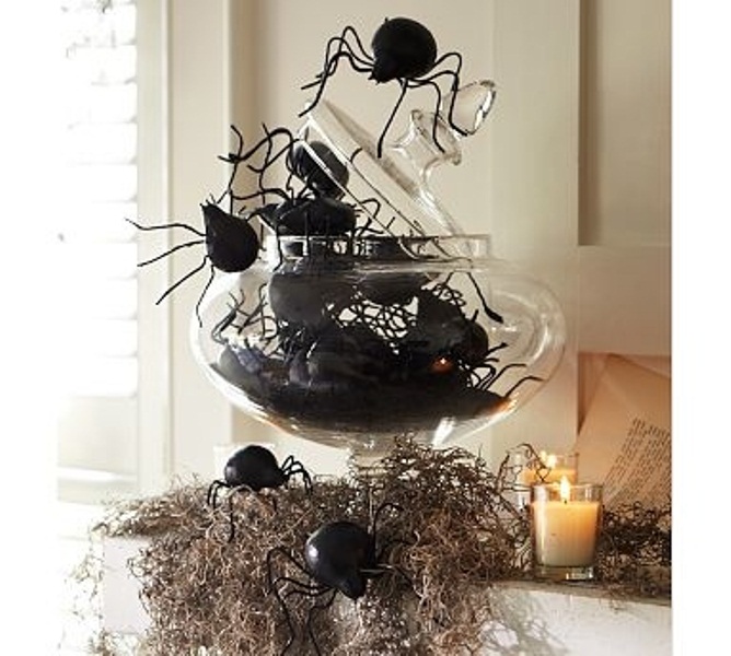 A scary Halloween decoration or centerpiece of hay, a glass jar with large spiders and candles is fantastic