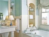 a vintage bathroom done in turquoise and neutrals, with a bathtub and niches with shelves, a large mirror and some curtains is very welcoming