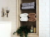a bathroom clad with white subway tiles and a niche done with an elegant gilded frame, with potted greenery and towels is a chic and creative idea