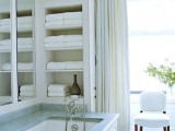 a neutral bathroom with a bathtub and a niceh by its side and some towels, this is a smart idea for seamless storage