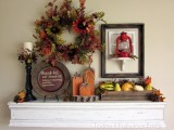 a decorative plate, a candle, a wooden box with faux veggies and fruit, a lantern, a faux leaf wreath and wooden pumpkins