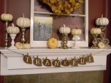 a leaf garland, white pumpkins on stands, a family pic and a fall leaf wreath over the mantel
