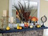 candles, faux pumpkins and gourds, bright fall leaves, feathers and faux leaves in a vase for a Thanksgiving mantel