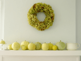 white, green and yellow pumpkins and a grene hydrangea wreath over the mantel are stylish Thanksgiving decor