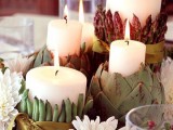 a porcelain bowl with candles wrapped with green beans, candles in artichokes and berries and blooms is a creative decoration