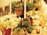 a harvest centerpiece of pears, berries and artichokes, veggies, candles and blooms is a stylish Thanksgiving idea
