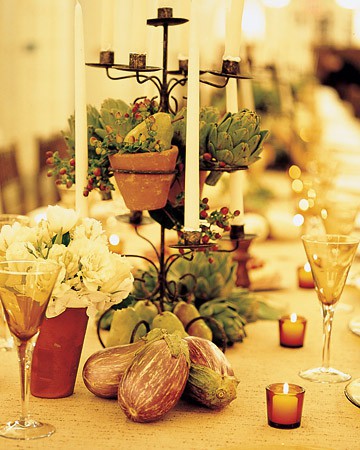a harvest centerpiece of pears, berries and artichokes, veggies, candles and blooms is a stylish Thanksgiving idea