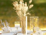 a neutral fall or Thanksgiving centerpiece of dried wheat, berries in a stained glass and a candle in a candleholder
