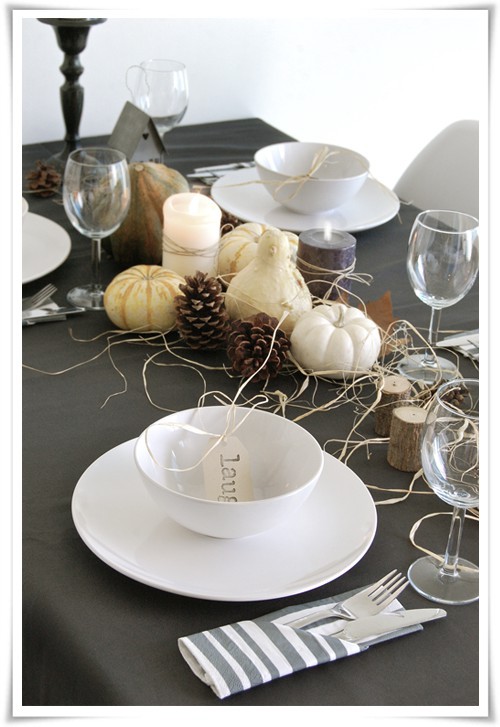 a Thanksgiving centerpiece of gourds, pumpkins, pinecones, candles, hay and tree stumps is very natural and rustic