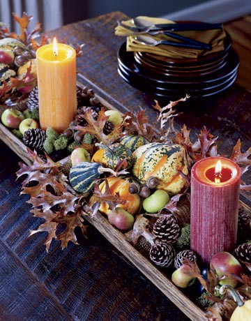 a wooden bowl with acorns, nuts, pinecones, gourds, pumpkins and candles is a cozy rustic idea of a centerpiece