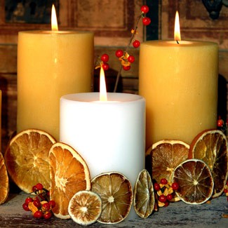 a natural fall centerpiece of tan and white candles covered with dried citrus and berries is a nice idea that you can easily make