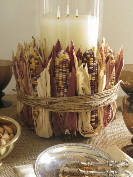 a large candle covered with corn cobs and husks is a beautiful rustic centerpiece for Thanksgiving