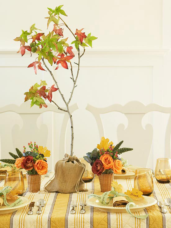 a fall centerpiece of bright blooms in baskets and a mini tree in burlap is a very creative idea