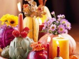 a porcelain bowl with pumpkins, cabbages, artichokes, pears, bright blooms and bold candles is a creative harvest centerpiece