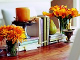 a simple Thanksgiving centerpiece of bright blooms in glass vases and a rust-colored candle in a candleholder