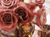 a clear vase with muted pink roses is a lovely fall centerpiece that can be also used for Thanksgiving