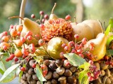 an acorn covered basket with berries, pears and blooms is a bold and creative harvest centerpiece for Thanksgiving