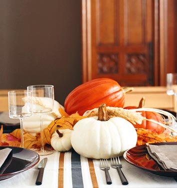an all natural Thanksgiving centerpiece of orange and white pumpkins, wheat, leaves are all you need to make your table cozy