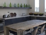 a moody kitchen with an open shelf and a row of green bottles that add color and highlight the vintage feel in the space