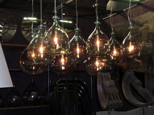 an arrangement of pendant lamps made of bottles hanging down is cool for any space